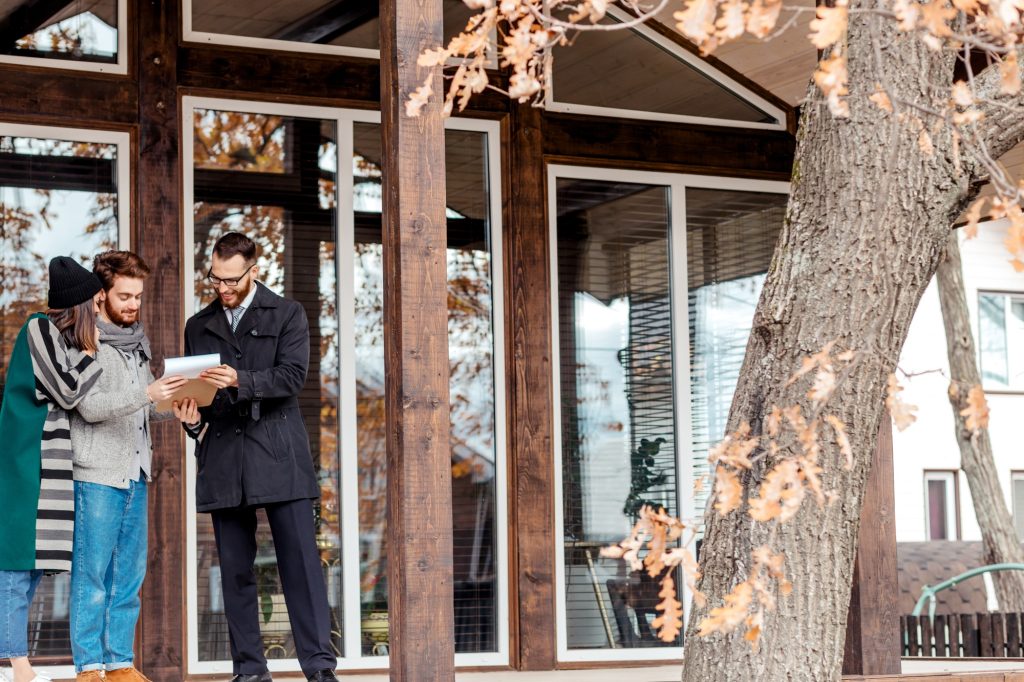 Young couple with real estate agent near house, real estate purchase
